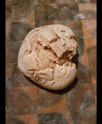 Ein braun gebackenes Brötchen liegt auf einem Schneidebrett.