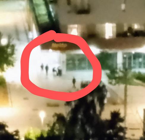 unscharfer Bildauschnitt zeigt schemenhaft Silhouetten von Personen an einer beleuchteten Häuserecke. Eine Person sitzt am Klavier und spielt.