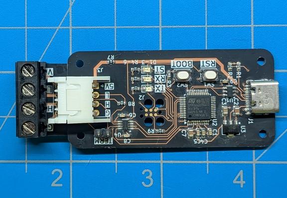 The same circuit board, with parts soldered on it. It has another small board plugged into the 4-pin connector, which breaks out the connector into a larger terminal block for connecting wires.