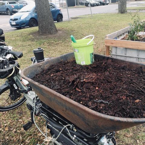An ebike-mounted wheelbarrow tub, filled with matured compost