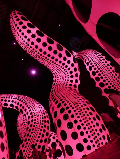 Enormous pink inflatable shapes - like tentacles - soar high above, illuminated from within. they bathe viewers in soft light, and warmth