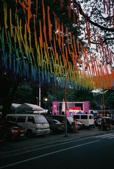 Rainbow banderitas in the overhead of parked cars.