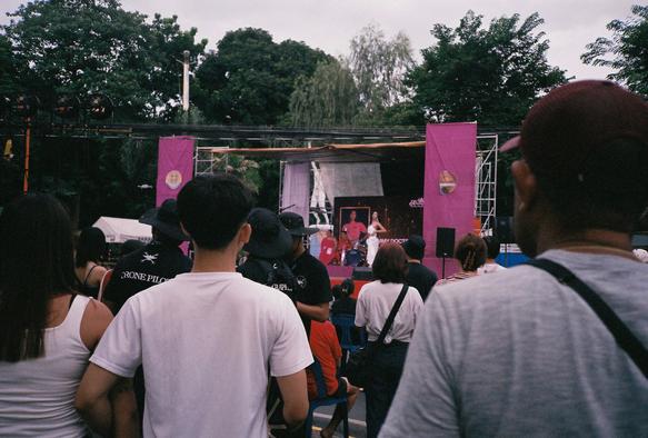 A pack of people watching the stage ahead where a drag performer is doing a catwalk.