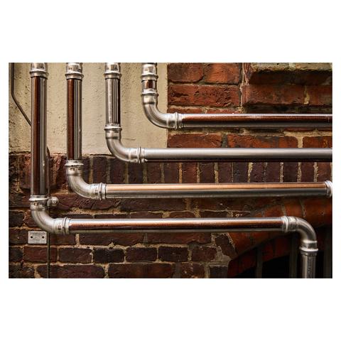 Closeup of four metal pipes running in parallel on the exterior of a red brick building facade.
