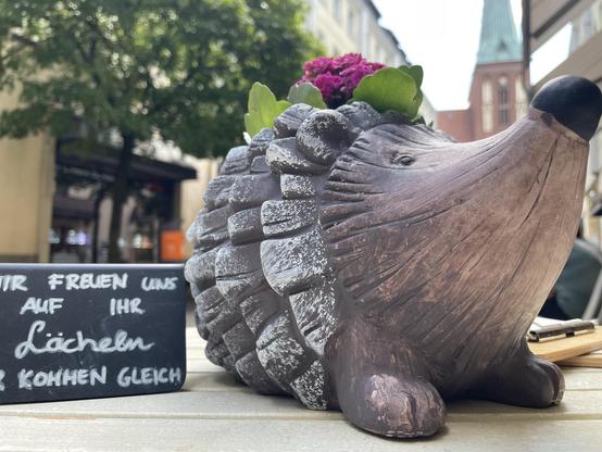 Tischdeko: ein Holzigel mit pinkfarbenen Blümchen.