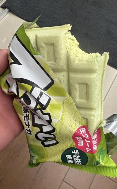 ファミマの店内ででっかい抹茶モナカのパッケージを破いて半分中身を出して、右上部分の稼働。少しかじって中身が見えている。