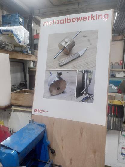 A poster in a workshop. The text at the top reads."Metaalbewerking" and includes 3 pictures of projects. The top picture is a Woodworking marking gauge and marking knife made of brass, steel, and ash wood. Bottom left is a photo of a close up of the marking gauge. Bottom right is a picture of a piece of metal in a vice with a tap wrench, and tap follower setup to thread one of the holes. In the bottom corner is a logo and text for "makerspace Leiden" around the poster are various tools including some fine files.