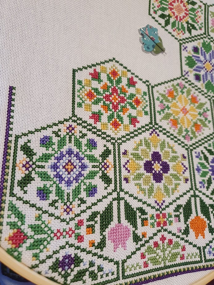 Photo showing progress of floral hexagon SAL. Dark green hexagons filled with bright coloured flowers.