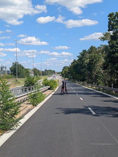 Ein Lastenrad fährt auf den Frankemschnellweg über die Auffahrt an der Jansenbrücke. Die Stadtautobahn im Hintergrund ist komplett leer.