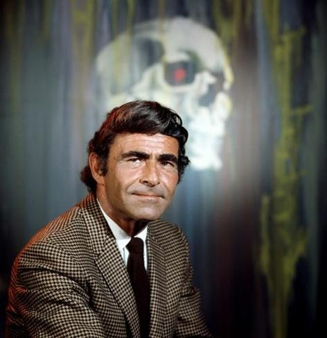 color promo pic of rod serling in front of a painting of a skull, in his night gallery days. he's a little older than the twilight zone days, hair a little longer, and he is (as ever) earth-shatteringly sexy