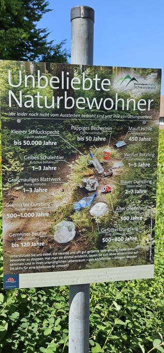 Bild zeigt ein Schild mit den unbeliebten Naturbewohnern in Form von verschiedenen Müllarten wie z.B. eine Plastikflasche, die 500-1000 Jahre braucht, um zu verrotten.