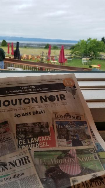 Une du journal le Mouton noir de juin 2025, reprenant plusieurs unes des 30 dernières années. 
En arrière-plan : la terrasse de la microbrasserie Tête d'Allumette (Kamouraska), avec le Saint-Laurent à marée basse.