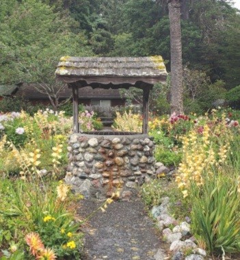 An old photo of a stone wishing well in a garden.