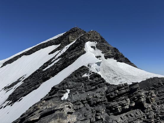 Summit of Balmhorn with summit cross and climbers around it, seen from the SE ridge just below the summit