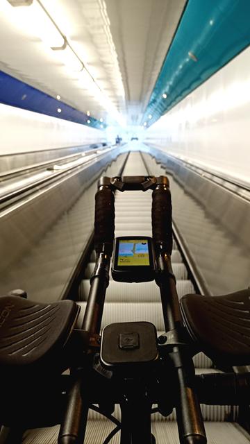Eine Rolltreppe im Fußgänger- und Radfahrertunnel in Rendsburg. Im Vordergrund ein Dropbarlenker mit Aerobar und Navigationsgerät.