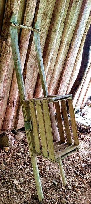 The described sled, leaning on a wall. The crate is sagging  a little and the skis still have some nailed on straps for slipping your boots into below the crate, from when they were used as skis.