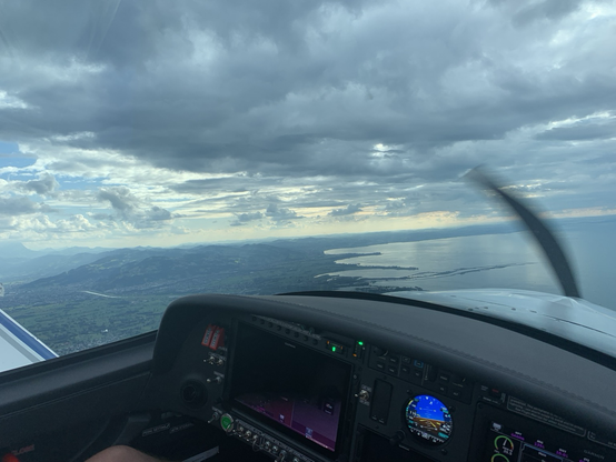 View out of a cockpit along the shore line. On top are clouds.
