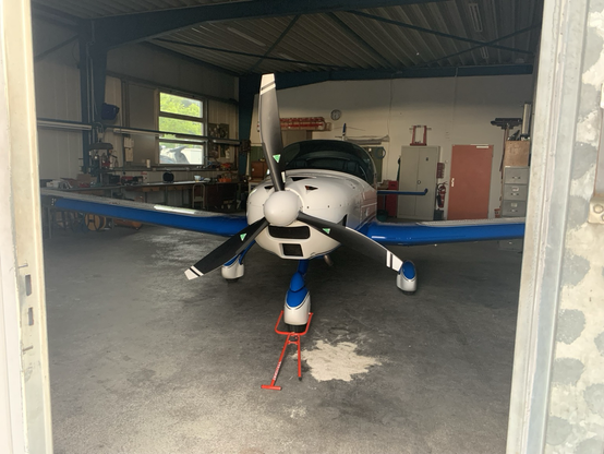 A small plane sneaking through a hanger door.