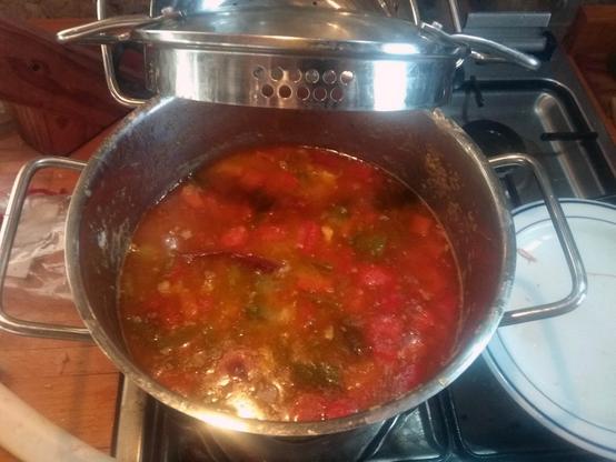 Olla con el gumbo casi hecho, un caldo de marcado color rojizo.