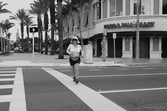 Woman jogging and crossing the street in B&W