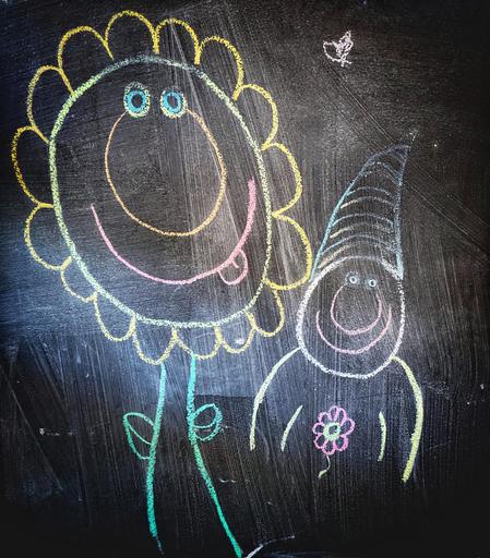 This image features a small section of a chalkboard wall at a local café. Profiled are two characters...the first is a sunflower with a big grin - complete with pink tongue and blue eyes. Beside the giant flower is a person with a log, soft toque, another goofy grin annd a flower on the shirt front.