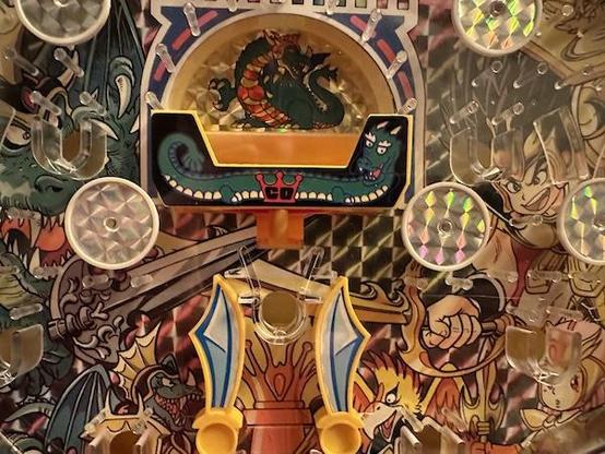 A toy pachinko center attraction, a dragon sits and a go switch drops down into an area guarded by dragons-wing-swords