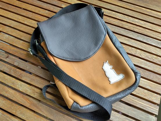 A version of the bag made from leather scraps. It has a white low poly fox icon sewed onto the front.
