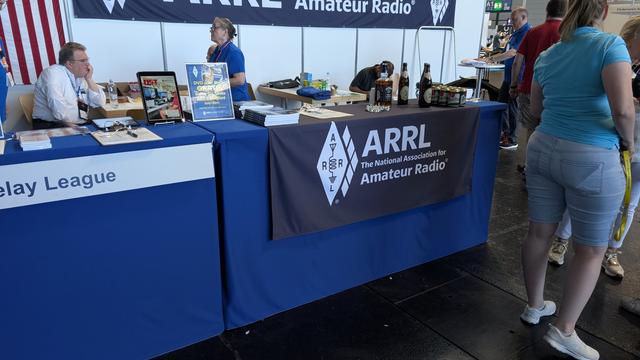 ARRL presence at HamRadio.
In the background some boring people, in the foreground on the desk a bottle american whiskey and german beer.