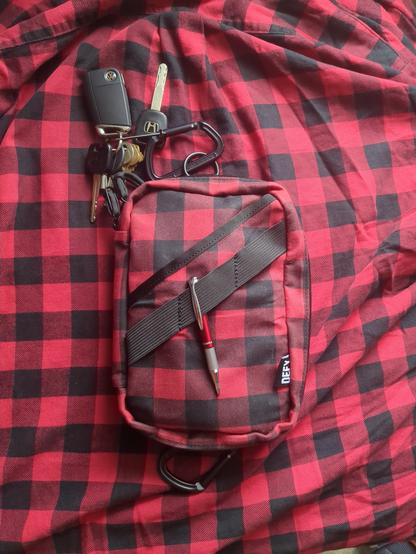 A red and black plaid bag resting on a similar red and black plaid shirt.