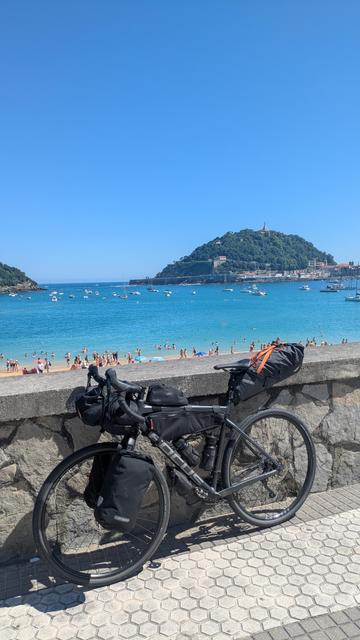 Bicycle leaning against a stone wall with the beach and the ocean in the background.