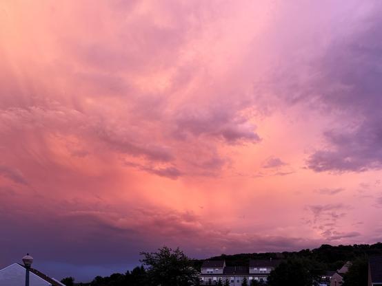 Cloudy sunset after a storm over houses with colors or purple, pink, and orange.
