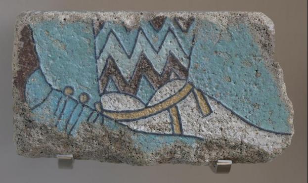 A foot and shin in zigzag-patterned trousers and low shoes laced all around the ankle