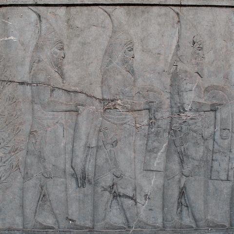 A relief of three delegates in pointed hoods, long coats, trousers and shoes with large daggers hanging at their right thighs.