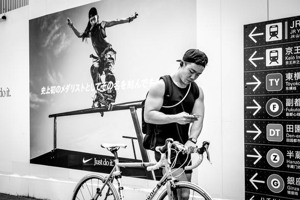 Ciclista davant d'una tanca publicitària amb una skater