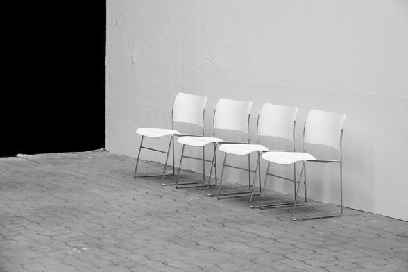 Four white chairs close to a wall
