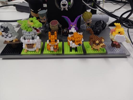 A number of Lego figures on the first plane. From left to right: An Owl, a hamster, a squirrel, a fox, a dog and a bird. There's a dinossaurd behind. Some figures of pokemon, JoJo bizarre adventures and elden ring too.