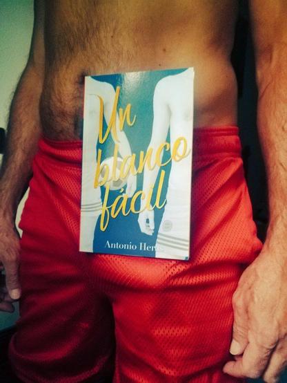 libro sujetado por algo que sobresale en pantalón rojo de hombre sin camiseta