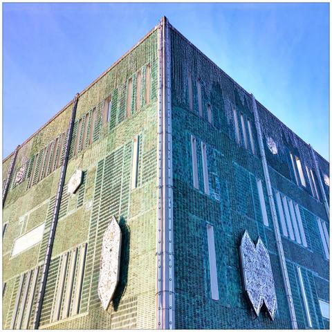 Frog’s-eye view of the decorated facades at the corner of a building under a blue sky.