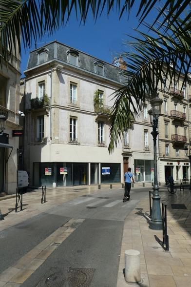On a sunny day, we see someone on an electric scooter on boulevard in the city of Nîmes, in France.