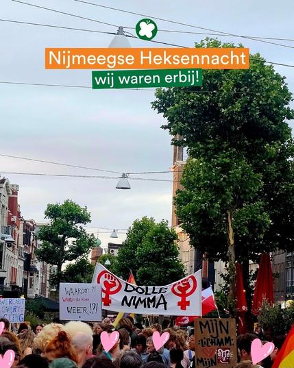 Een grote menigte demonstranten marcheert door een straat in Nijmegen tijdens de Heksennacht 2025. Borden met feministische leuzen en symbolen zijn zichtbaar, waaronder een spandoek met "Dolle Nimma" en een bord met "Waarom?! Waarom sta ik hier weer!?". Bovenaan staat een overlay met de tekst: “Nijmeegse Heksennacht – wij waren erbij!”.