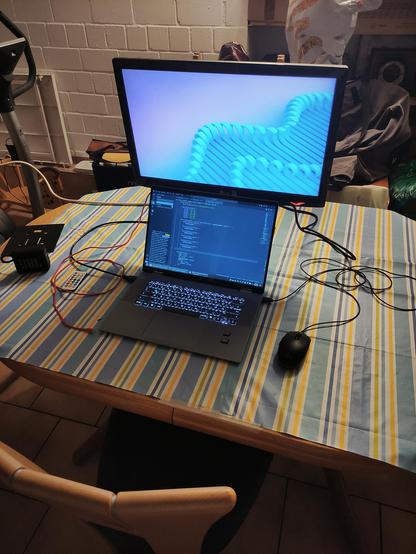 Laptop on desk with striped table cloth and secondary monitor