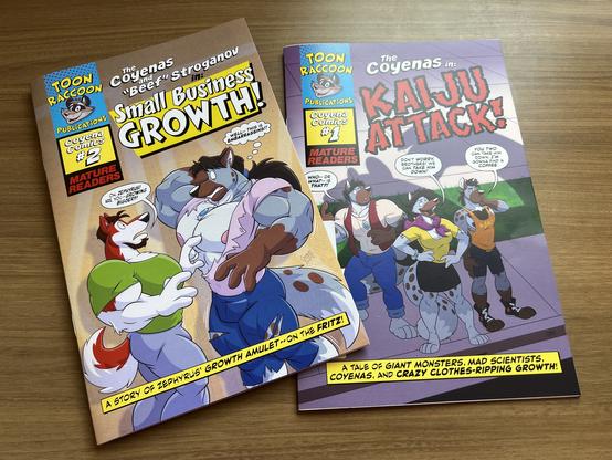Photo of the covers of two comic books: Coyena Comics #1: Kaiju Attack! showing the three coyena siblings looking up while standing in the shadow of a large monster; and Coyena Comics #2: Small Business Growth! showing wolfdog Beef Stroganov surprised as he's just seen coyena Zephyrus grow big enough to rip out of his shirt.