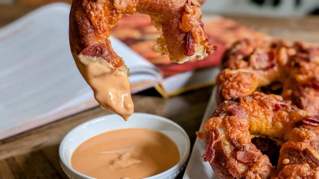 A soft pretzel dipped in orange sauce.