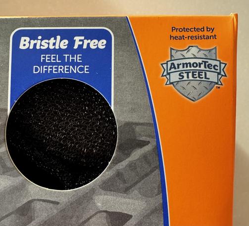 Front of the orange packaging, top right corner. A cut-out enables customer to FEEL THE DIFFERENCE of the "Bristle Free" sponge.