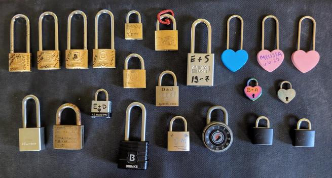 An assortment of 22 love locks, laid out nicely on a black mat.
