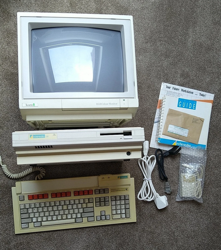 A picture of the Acorn Archimedes A310, monitor, keyboard, mouse, documentation, and cables laid out on a carpeted floor.