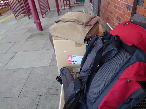 A picture of a rucksack containing the Archimedes, and a box for the monitor sitting on a bench at Llandudno train station.