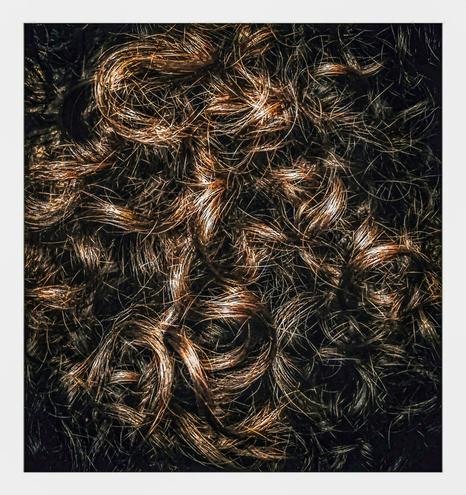 This photo is a close-up shot of a mass of dark brown, curly hair (mine). The strands are tightly interwoven helping to create a dense and textured surface. Some strands are highlighted while other are in shadow creating some depth.