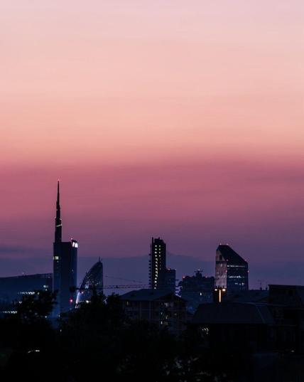 Skyline of Milan, Italy at dusk, with orange and purple hues.