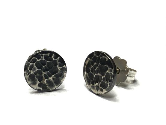 A pair of round, textured earrings featuring a black and white speckled design, set against a plain white background.